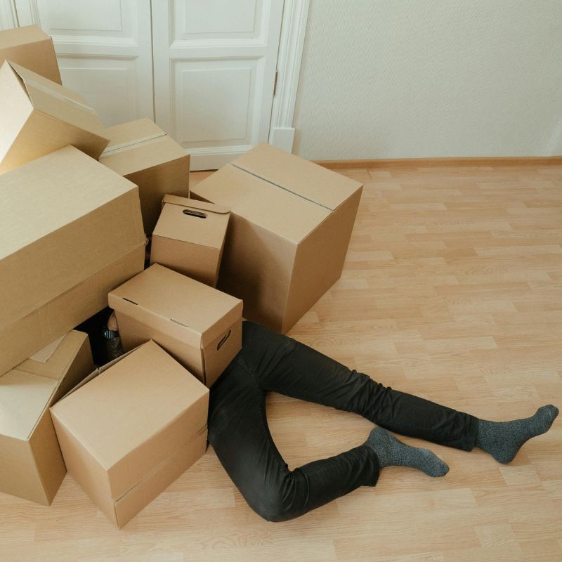 personne couchée sous carton de déménagement